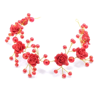 Detailed macro view of handmade bridal hair vine with red roses, pearls and gold wire