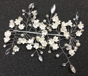 Détail d'une vigne de cheveux de mariée avec fleurs blanches, perles et cristaux