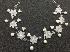Détail de vigne à cheveux mariée avec fleurs blanches mates, perles et tissage argenté
