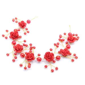 Detailed view of handmade red resin roses and pearls on a gold bridal hair vine