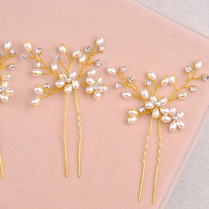 Close-up of handmade bridal hair pin with pearls and crystals on a gold leaf-shaped wire