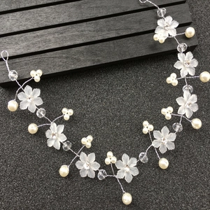 Détail de vigne de cheveux de mariée avec fleurs mates, perles crème et cristaux argentés