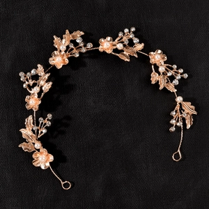 Detailed macro of bridal headband with rose gold metal leaves and pearl flowers
