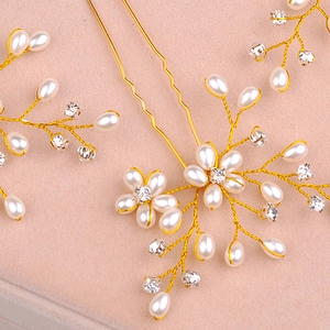 Close-up of handmade bridal hair pins with golden wires, pearls and crystals