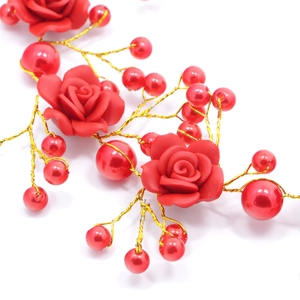Close-up of bridal headband with red resin roses and pearls on golden wire weave