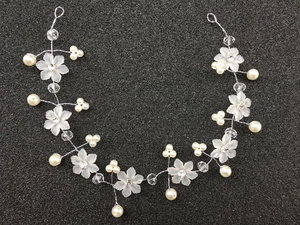 Détail d'un accessoire cheveux de mariée fait main avec fleurs givrées et perles
