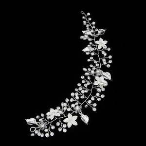 Dettaglio di un accessorio sposa fatto a mano con fiori in resina bianca e strass lucidi