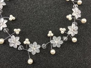 Gros plan sur un bandeau de mariée avec fleurs givrées et perles sur fil argenté