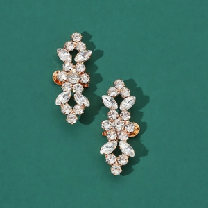Detailed close-up of vintage rhinestone shoe clips with gold plating on a green background