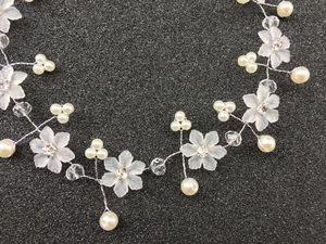 Détail de vigne de cheveux de mariée avec fleurs mates, perles et cristaux sur fil d'argent