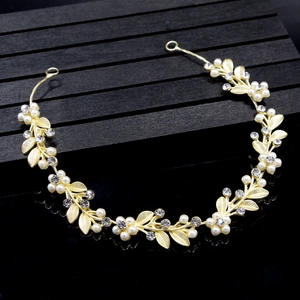 Detail of golden leaf bridal hairpiece with pearls and rhinestones on a black background