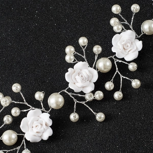 Handmade bridal hair vine with white ceramic roses and pearls on a black background