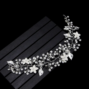 Dettaglio di accessorio per capelli da sposa con fiori bianchi, perle e cristalli