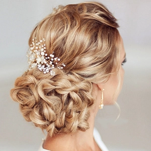 Nahaufnahme eines Braut-Haarkamms mit Perlen und Kristallen auf einem goldenen Dutt