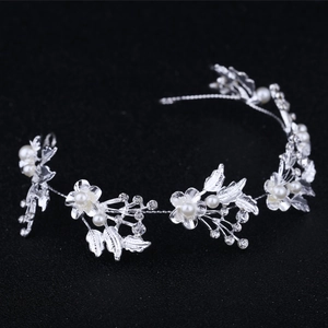 Silver bridal headband with crystal flowers and white pearls on a dark background