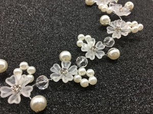 Détail de bijoux de tête pour mariée avec fleurs givrées et perles blanches polies