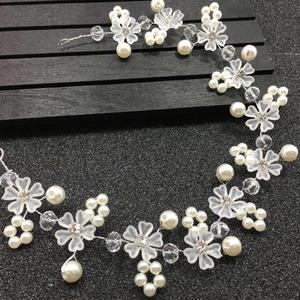 Détail d'une vigne de cheveux de mariée avec fleurs mates, perles et cristaux sur noir