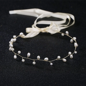 Detail of handmade bridal headband with pearls and gold wire on black background