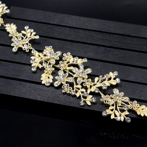 Close-up of golden leaf hairpiece with sparkling rhinestones on black wood base