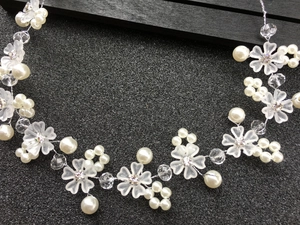 Détail d'un bandeau de mariée avec fleurs mates, perles blanches et fil d'argent tissé