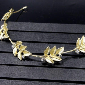 Close-up detail of golden leaf bridal headband with sparkling rhinestone flower clusters