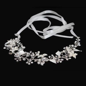 Dettaglio macro della fascia da sposa con foglie bianche, perle e cristalli su nero