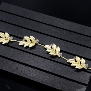 Close-up of golden leaf headpiece with rhinestones on a rustic black wooden background