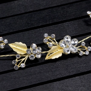 Detailed close-up of bridal hair vine with golden metal leaves and sparkling rhinestones
