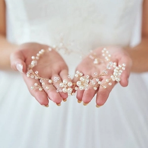 Détail du bandeau de mariée fait main avec perles et cristaux sur fond de robe blanche