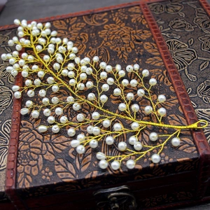 Détail d'un peigne à cheveux de mariée fait main avec fils dorés et perles blanches