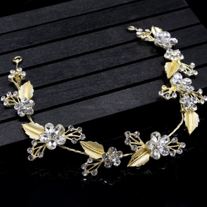 Close-up of handmade gold leaf hairband with crystal flowers on a black textured stand