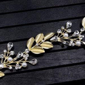 Macro shot of gold leaf details with white pearls and rhinestones on a bridal hair vine