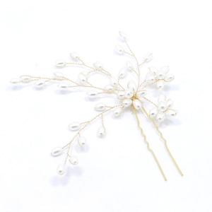 Close-up of handmade bridal hair pin with pearls and golden wire in a floral branch design