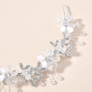 Détail d'un serre-tête de mariée argenté avec des fleurs en cristal et perles blanches