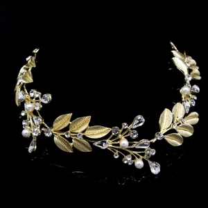 Close-up of golden leaf hairband with delicate pearls and sparkling crystals on black surface