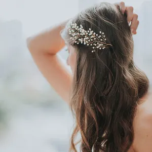 Détail d'un peigne de mariée avec branches dorées et perles sur cheveux ondulés
