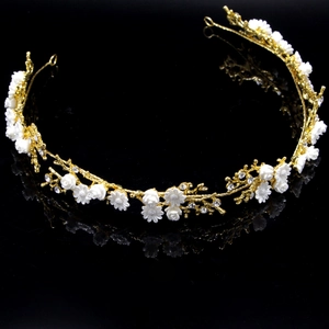 Detailed close-up of golden bridal headband with white flowers and sparkling rhinestones