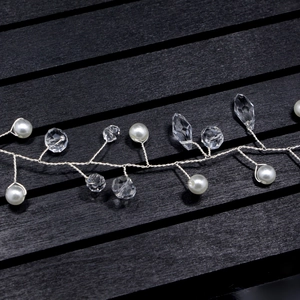 Detail of silver wire bridal hairpiece with white pearls and faceted crystals on wood