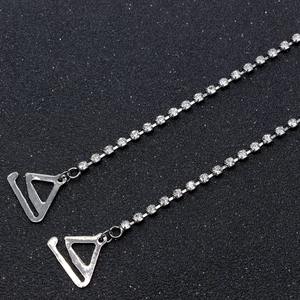Dettaglio macro di spalline per reggiseno argento con fila di strass chiari scintillanti