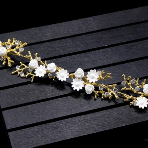 Detail shot of white rhinestone flowers on elegant gold floral bridal hairband