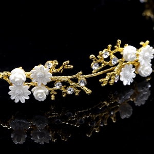 Detailed macro view of white floral bridal headband with gold plating and sparkling crystals