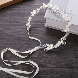White floral bridal headband with silver metal branches and ribbons on wood background