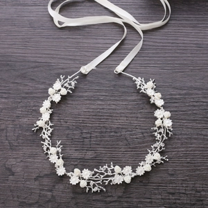 Elegant silver bridal headband with white flowers and satin ribbons on a wood background