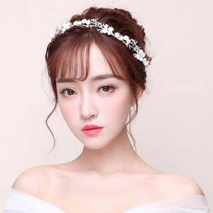 Detailed view of white floral bridal headband with rhinestones on a woman's hair