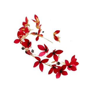 Dettaglio di accessorio per capelli con fiori rossi fatti a mano e foglie dorate