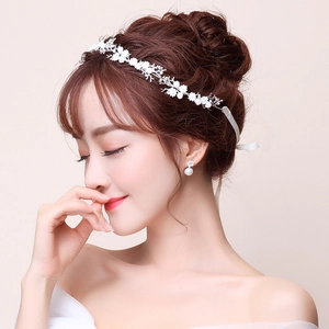 Detail view of bridal headpiece with white flowers and matching pearl earrings