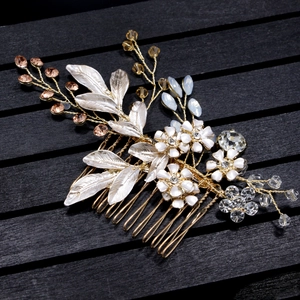 Exquisite gold bridal hair comb with white flowers, amber beads, and crystals on a wood base