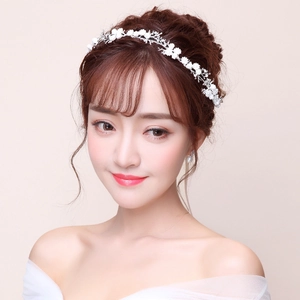 Close-up of white floral bridal headband with silver leaves and pearls on model
