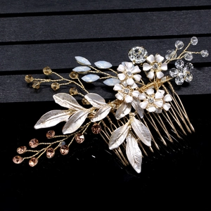 Detailed close-up of handmade bridal hair comb with white flowers, gold leaves and rhinestones