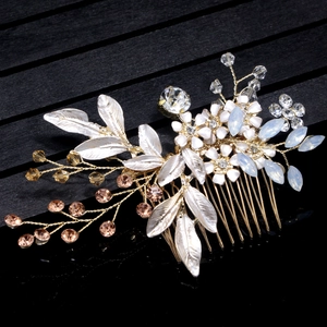 Close-up of golden bridal hair comb with blue rhinestones and white enamel flowers